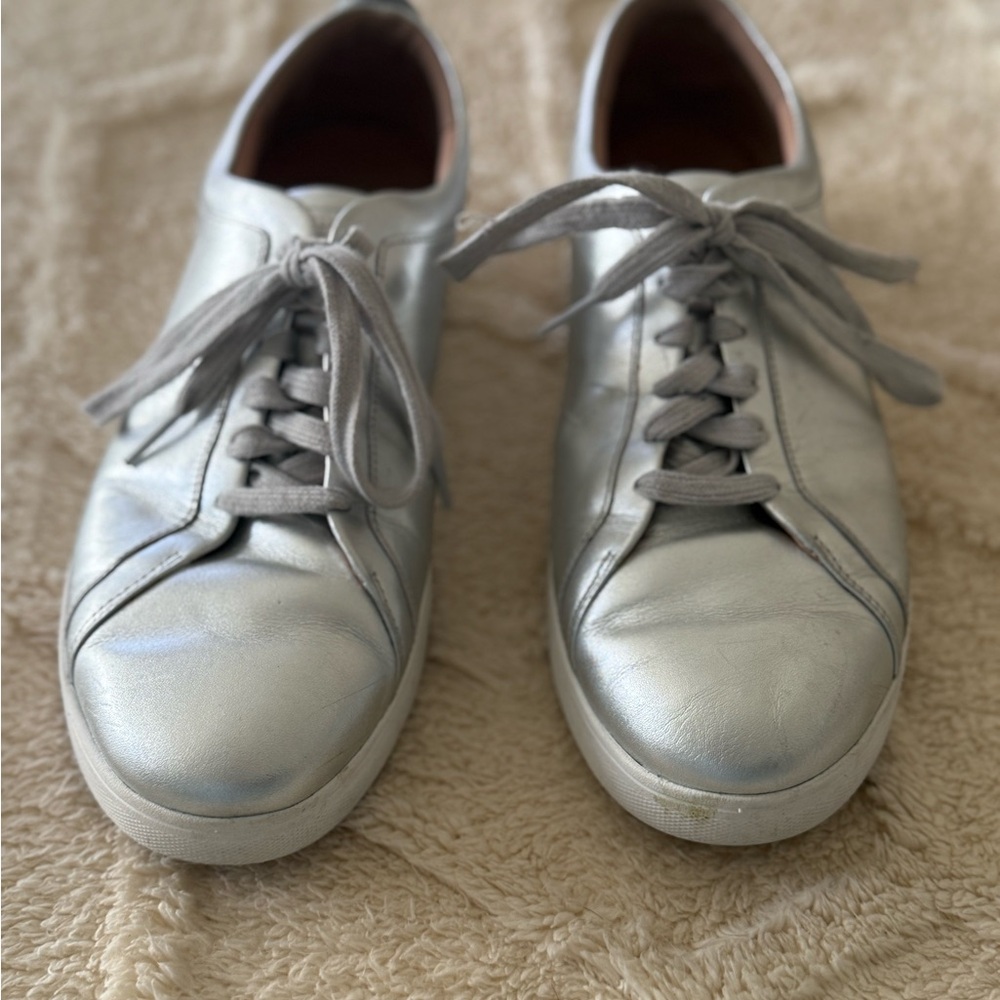 Silver low-top sneakers with a metallic finish and white laces